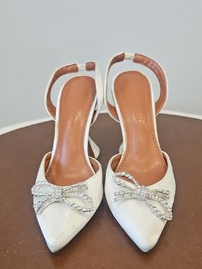 Amina Muaddi White Pointed Slingback Heels with Crystal Bow